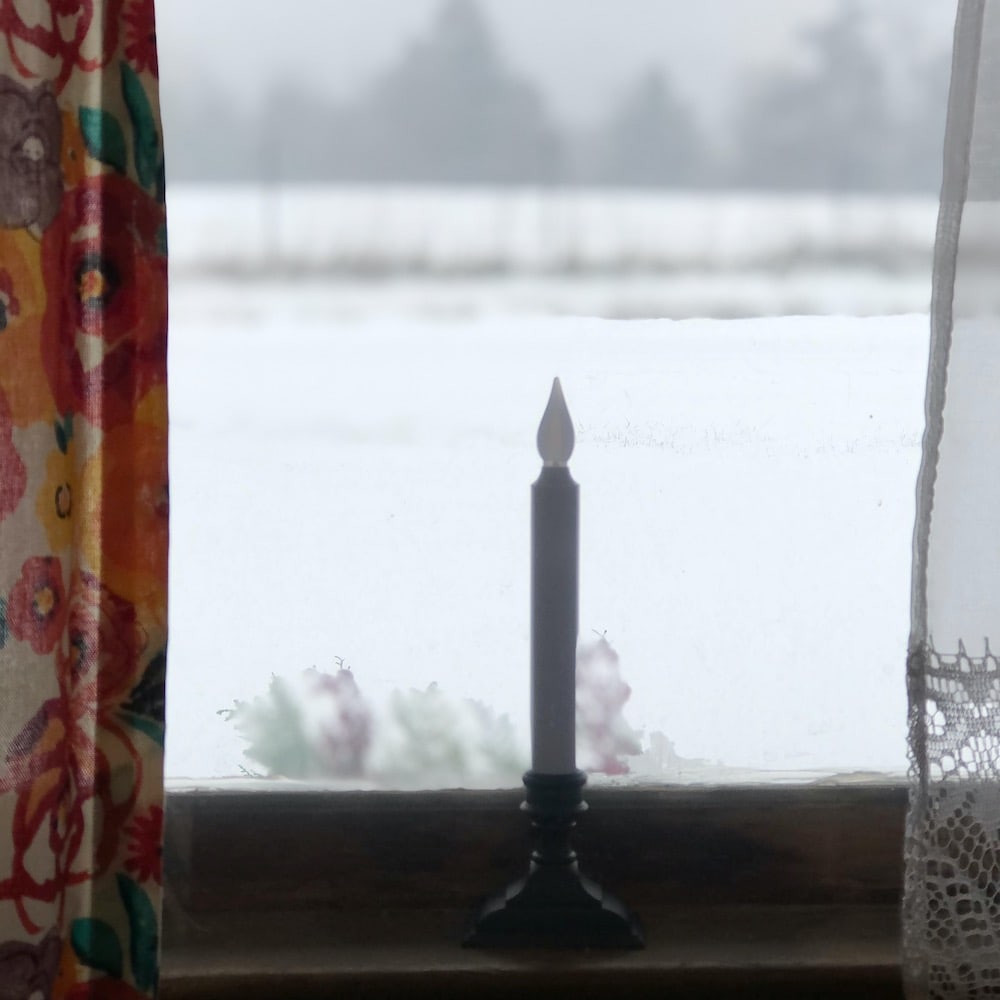 candle on windowsill with background of freshly fallen snow