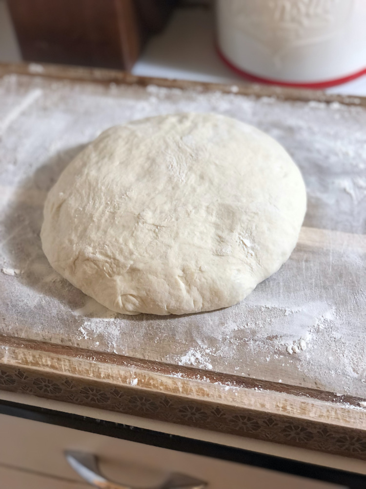 bread dough resting on a floured wooden cutting board