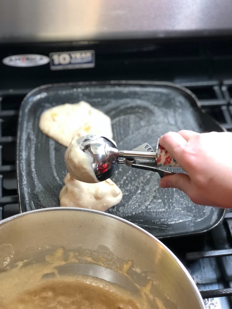 pancake batter being poured onto griddle